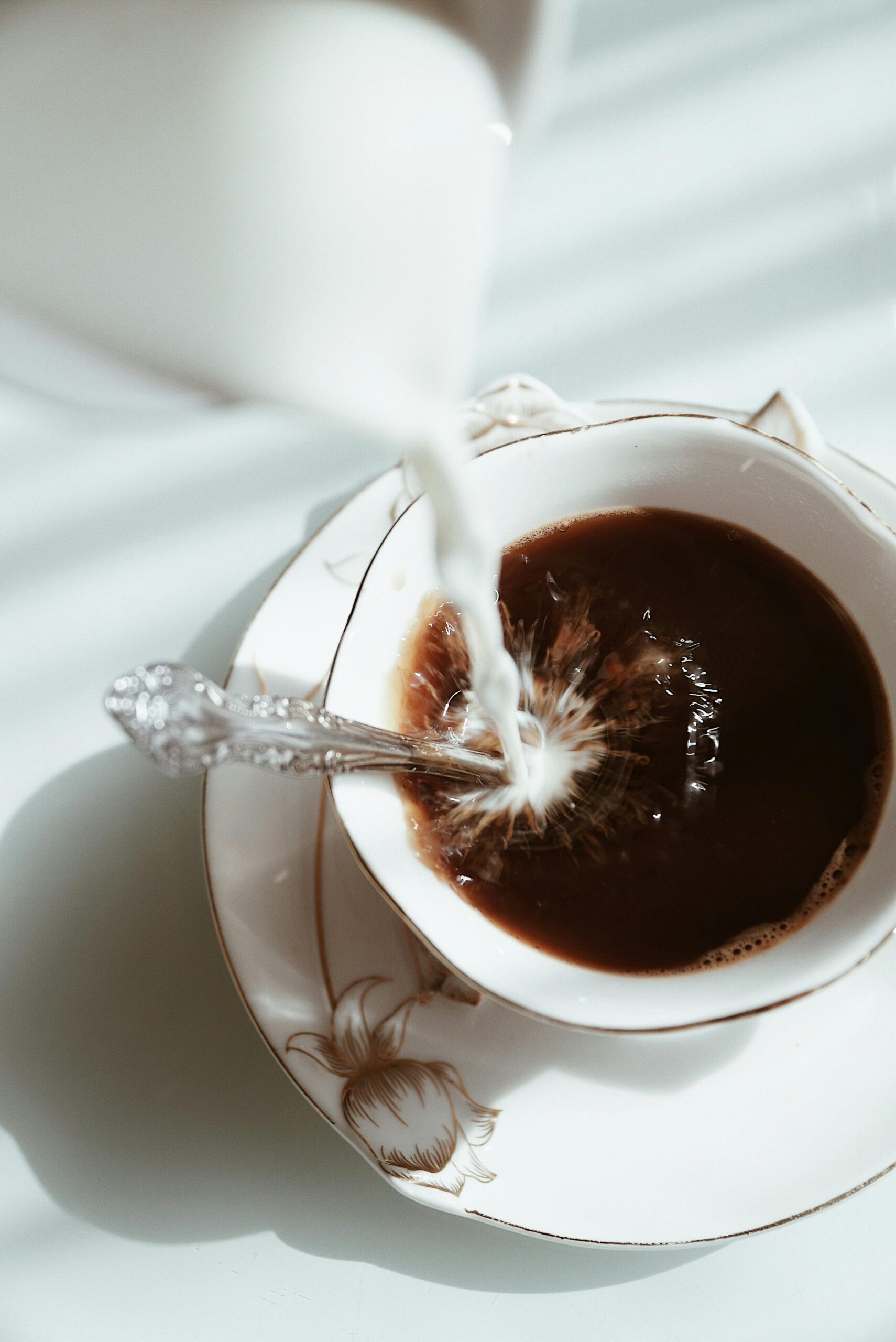 Milk being poured into coffee in morning light